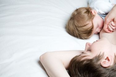 Eine Mutter die mit ihrem Kind im Bett liegt und dieses stillt